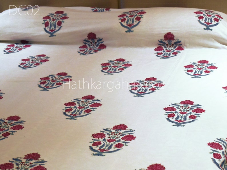 May include: White cotton bedding with a repeating floral pattern in shades of pink and blue. The pattern is a traditional Indian design. The text "DC02" is visible in the top left corner of the image.