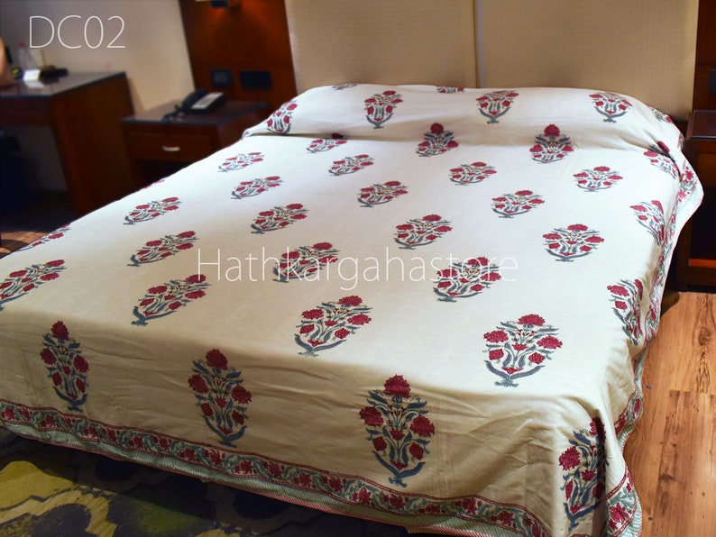 May include: A white bedspread with a red and blue floral pattern. The bedspread is on a bed with a wooden headboard. The text "DC02" and "Hathkaraghastore" are visible in the image.