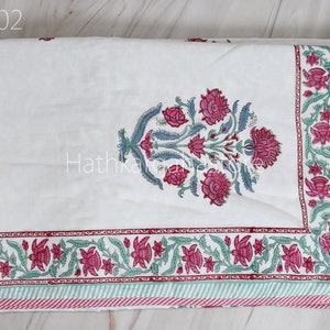 May include: White cotton quilt with a pink and green floral print. The quilt has a border of pink and green flowers and a striped border in pink and green.