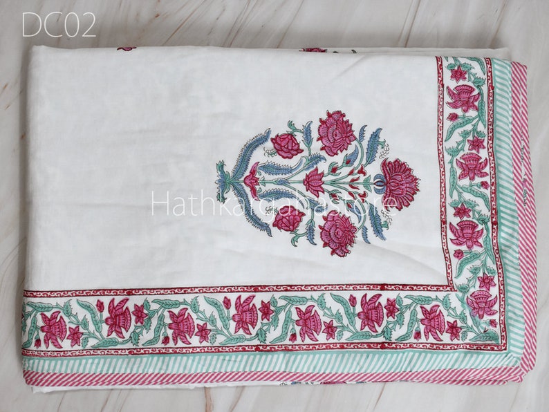 May include: White cotton quilt with a pink and green floral print. The quilt has a border of pink and green flowers and a striped border in pink and green.