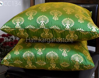 May include: Two green and gold throw pillows with a traditional Indian design. The pillows are stacked on top of each other and have a gold trim.