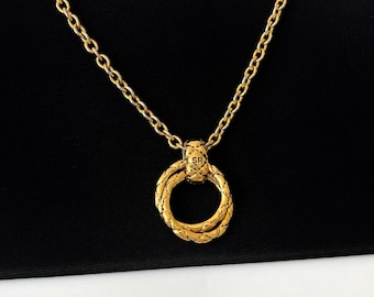 Puede incluir: Un collar de cadena de oro con un colgante de anillo de oro. El anillo es de doble capa y tiene una superficie texturizada. El colgante tiene las letras "SR" grabadas.