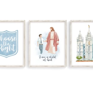 May include: Three framed prints with watercolor illustrations. The first print features a blue shield with the text "Choose the Right". The second print shows a man in a red robe holding the hand of a boy in a blue shirt and tie. The text below reads "I am a child of God". The third print shows a white building with multiple spires.