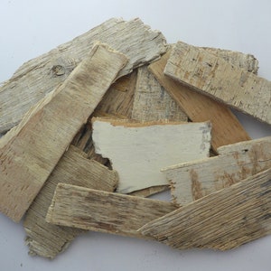 Könnte beinhalten: Ein Stapel verwitterter Holzreste in verschiedenen Größen und Formen, einige mit einer weißen lackierten Oberfläche.