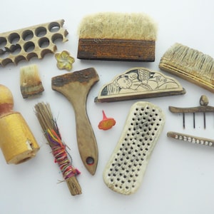 May include: A collection of vintage wooden tools and decorative items, including brushes, a small rake, and a carved wooden piece with a floral design. The items are in various shades of brown and beige.