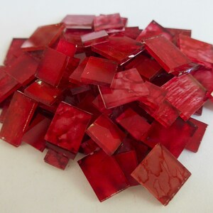 Peut inclure: Un tas de petits carreaux de verre rouge. Les carreaux sont carrés et ont une finition légèrement irisée.