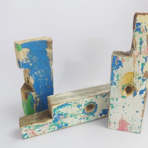 May include: Two wooden blocks painted in shades of blue, green, white, and pink. The blocks are weathered and have a rustic look. They are arranged in an L-shape.
