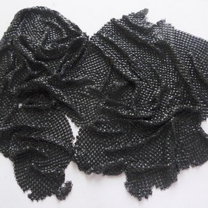 May include: Black chainmail fabric with a textured surface. The fabric is folded and draped on a white background.