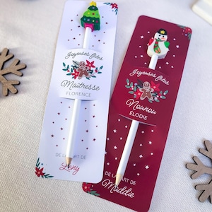 Könnte beinhalten: Zwei weiße Stifte auf rechteckigen Karten. Eine Karte ist weiß mit einem Weihnachtsbaum-Aufsatz, die andere dunkelrot mit einem Schneemann-Aufsatz. Beide zeigen Lebkuchenmann-Grafiken, den Text Joyeuses fêtes und Namen.