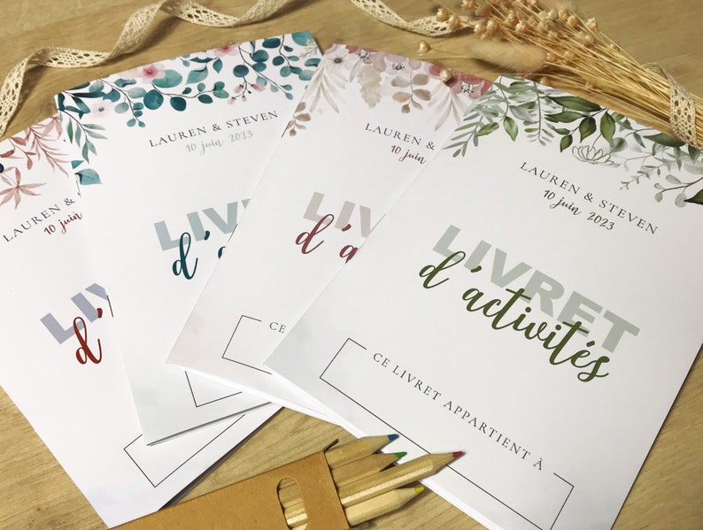 K&ouml;nnte beinhalten: Vier wei&szlig;e Aktivit&auml;tshefte mit floralen Illustrationen am oberen Rand, die den Text "LAUREN & STEVEN 10 juin 2023" und "LIVRET d'activit&eacute;s" sowie ein Feld f&uuml;r einen Namen unter "CE LIVRET APPARTIENT &Agrave;" enthalten.