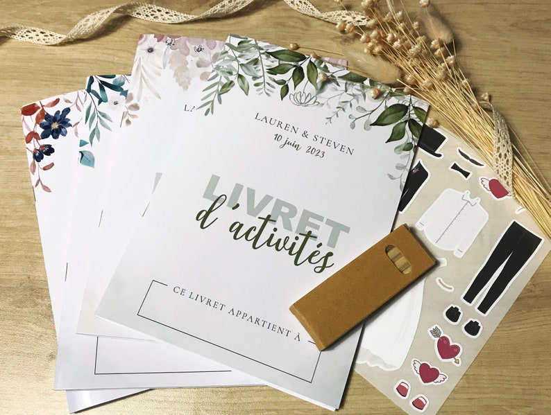 K&ouml;nnte beinhalten: Ein Stapel Aktivit&auml;tshefte mit Blumenillustrationen, mit dem Text LAUREN & STEVEN 10 juin 2023 LIVRET d'activit&eacute;s CE LIVRET APPARTIENT &Agrave;, dazu eine braune rechteckige Karte und ein Bogen mit Aufklebern von Kleidung und Herzen.