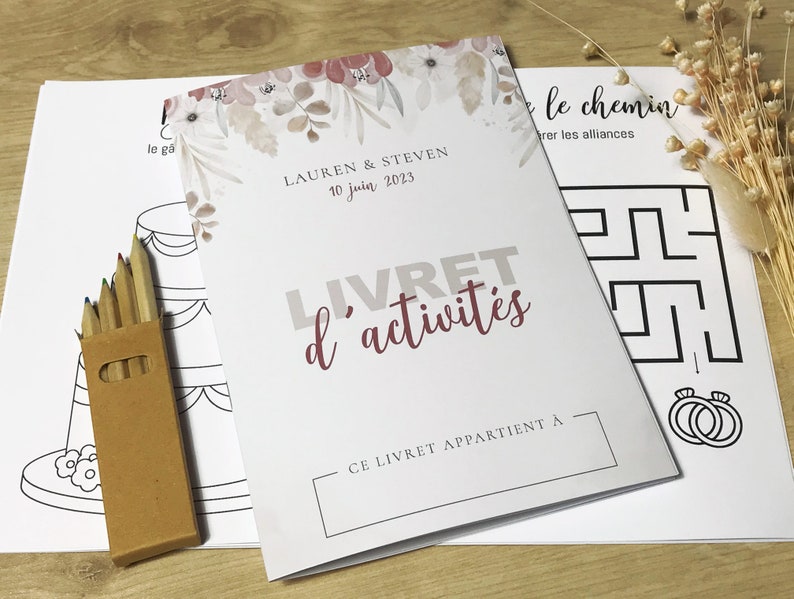 K&ouml;nnte beinhalten: Ein wei&szlig;es Aktivit&auml;tsheft mit dem Titel LIVRET d'activit&eacute;s, Blumenmotiven, den Namen Lauren & Steven und dem Datum 10 juin 2023. Es enth&auml;lt eine braune Pappschachtel mit Buntstiften und Bl&auml;tter mit schwarz-wei&szlig;en Strichzeichnungen.