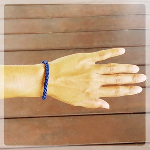 Puede incluir: Primer plano de una mano con una pulsera trenzada de color azul oscuro.