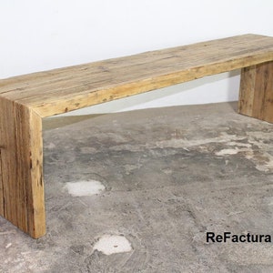 Pu&ograve; includere: Panca rustica in legno con piano rettangolare e due spessi supporti verticali. La panca &egrave; realizzata in legno di recupero, mostrando venature e nodi naturali. La panca &egrave; lunga circa 152 cm.