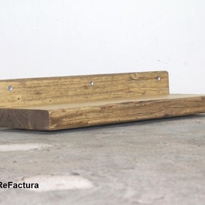 May include: A rustic wooden shelf with a natural finish. The shelf is made from reclaimed wood and has a unique, weathered look. It is perfect for adding a touch of rustic charm to any room.