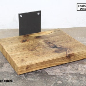May include: A rustic wooden shelf with a metal bracket. The shelf is made of reclaimed wood and has a natural finish. The bracket is black and has two holes for mounting.