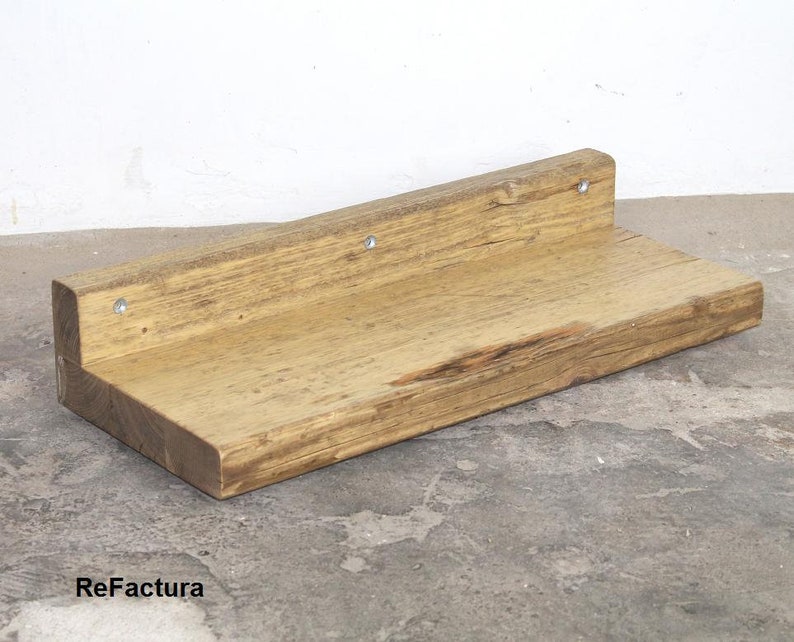May include: A rustic wooden shelf with a natural wood finish. The shelf is mounted to a wall with screws and has a slightly uneven surface.