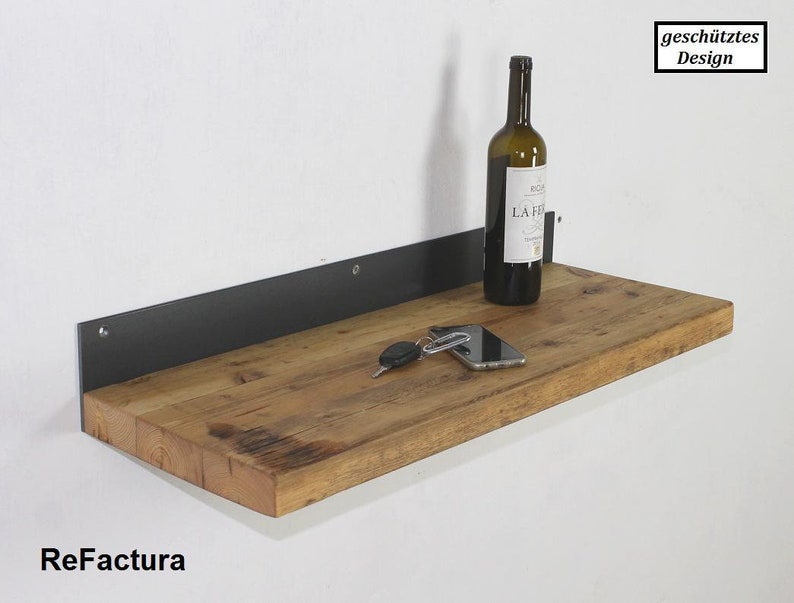 May include: A wooden shelf with a black metal bracket. The shelf is made of reclaimed wood and has a rustic look. A bottle of wine, a phone, and keys are on the shelf.