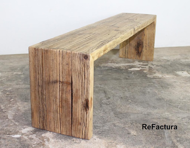 Pu&ograve; includere: Panca rustica in legno dall'aspetto naturale e invecchiato. La panca &egrave; costruita con spesse assi di legno di recupero, che mostrano venature e nodi visibili. Il design presenta una seduta rettangolare sostenuta da due gambe massicce a forma di blocco. La panca misura circa 152 cm di lunghezza.
