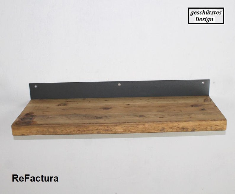 May include: A wooden shelf with a black metal bracket. The shelf is made of reclaimed wood and has a rustic look. The bracket is attached to the wall with screws. The shelf is labeled "ReFactura" in the bottom left corner. The text "gesch&uuml;tztes Design" is in a white rectangle in the top right corner.