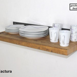 May include: A wooden shelf with a black metal bracket, holding white plates and mugs with purple designs. The shelf is labeled "ReFactura" and the bracket has a "gesch&uuml;tztes Design" label.
