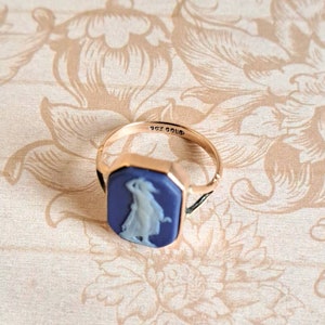 K&ouml;nnte beinhalten: Ein goldener Ring mit einem blauen Kamee, der eine Frau in einem wei&szlig;en Kleid zeigt. Der Ring ist mit "9ct GOLD 336" beschriftet.