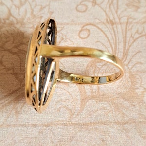 Pu&ograve; includere: Un anello d'oro con una grande pietra ovale incastonata in un design delicato e intricato. L'anello &egrave; contrassegnato "585" sulla fascia interna.
