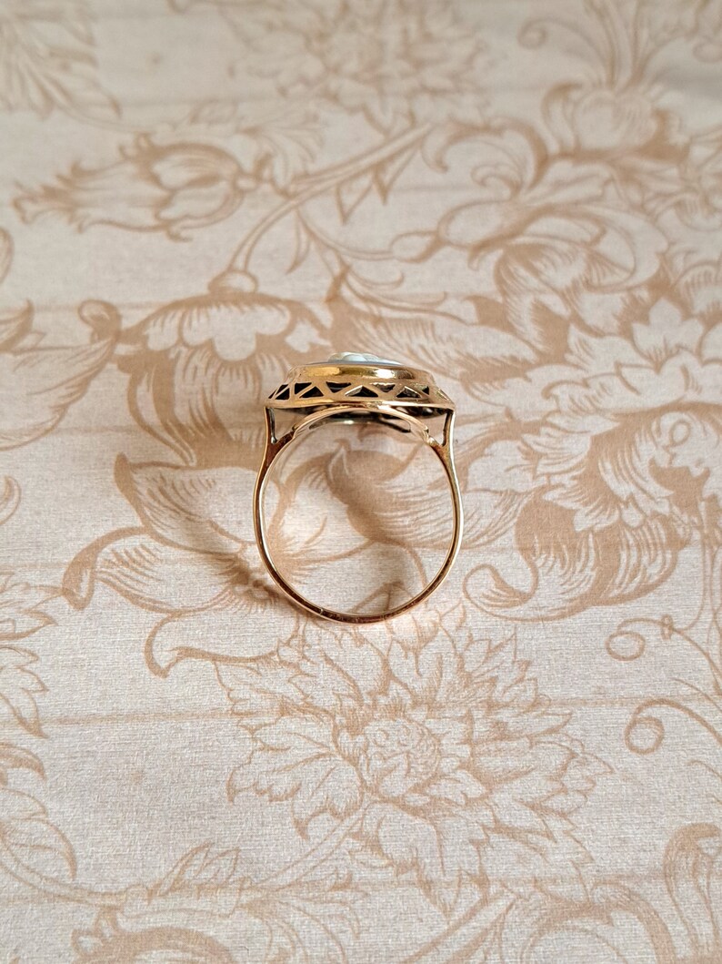 Pu&ograve; includere: Un anello d'oro con una pietra bianca incastonata in un design geometrico.
