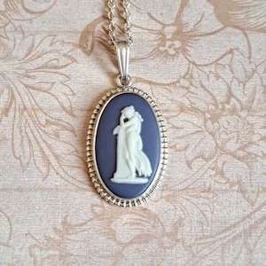 Può includere: Una collana con catena d'argento con un ciondolo ovale con un cammeo bianco di due figure su sfondo blu scuro.