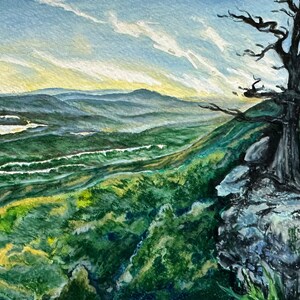 May include: A watercolor painting of a mountain landscape with a lone tree on a cliff overlooking a valley. The sky is a soft blue with wispy clouds, and the mountains are a deep green. The tree is bare and branches out towards the viewer.
