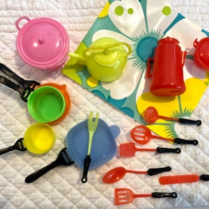 Puede incluir: Un conjunto de utensilios de cocina de juguete de plástico de colores. El conjunto incluye una olla rosa, una olla verde, una olla azul, una tetera amarilla, una jarra roja, una olla roja, una cuchara amarilla, una cuchara verde, una cuchara azul, una espátula roja, una espátula verde, una espátula azul, un tenedor rojo, un tenedor verde y un tenedor azul.