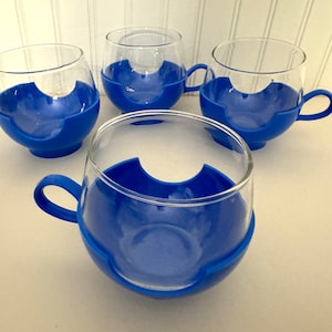 May include: Set of four blue glass mugs with clear glass cups and blue plastic handles. The mugs are designed to hold hot beverages.
