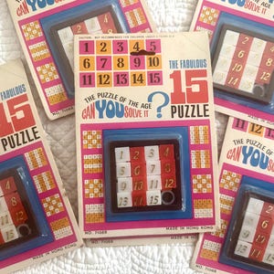以下が含まれることがあります： ヴィンテージの「The Fabulous 15 Puzzle」ゲームがいくつかあります。各ゲームには、赤、白、黒のフレームに番号付きのタイルが入ったプラスチック製のスライドパズルがあります。パッケージはピンク、青、白で、パズルの名前と「Can You Solve It?」のテキストが記載されています。