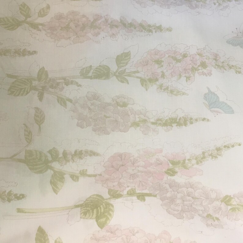 May include: A light-colored floral pattern featuring pink flower clusters, green leaves, and pale blue butterflies. The design is repeated across the surface, creating a soft, vintage aesthetic. The flowers and leaves are detailed with subtle shading.
