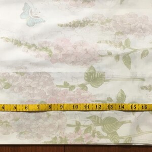 May include: White fabric with a floral and butterfly pattern. The design features pink flowers and green leaves on stems, with light blue and green butterflies. A yellow measuring tape shows a length of 21 inches.