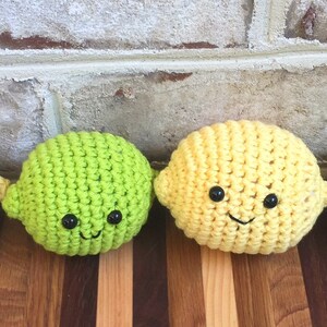 May include: Four crocheted lemon and lime plush toys with smiling faces. The toys are yellow and green and have black eyes and mouths.