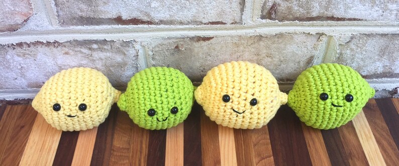 May include: Four crocheted lemon and lime plush toys with smiling faces. The toys are yellow and green and have black eyes and mouths.
