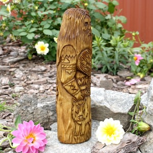 K&ouml;nnte beinhalten: Eine Holzschnitzerei eines nordischen Gottes, m&ouml;glicherweise Odin, mit Bart und einem Wolf zu seinen F&uuml;&szlig;en. Die Schnitzerei ist detailliert und kunstvoll, mit einem Schild und anderen Symbolen, die in das Holz geschnitzt sind.