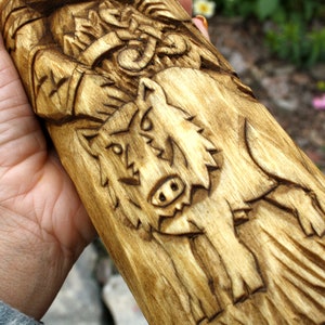 K&ouml;nnte beinhalten: Handgeschnitzte Holzfigur eines nordischen Gottes mit einem Wolf an seiner Seite. Die Figur ist aus hellbraunem Holz gefertigt und hat eine detaillierte Schnitzerei des Gesichts und des Bartes des Gottes. Der Wolf ist ebenfalls detailliert geschnitzt und hat einen grimmigen Ausdruck.