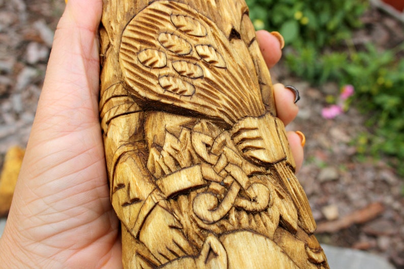 K&ouml;nnte beinhalten: Eine Holzschnitzerei einer Figur, die eine Garbe Weizen h&auml;lt. Die Schnitzerei ist detailliert und kunstvoll, mit einem Fokus auf die H&auml;nde der Figur und den Weizen.