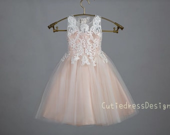 May include: A blush pink tulle dress with white lace detailing and a sleeveless design. The dress is hanging on a gold hanger. The text "CutiedressDesign" is visible at the bottom of the image.
