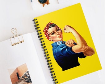 May include: A yellow spiral notebook with a vintage illustration of a woman flexing her bicep. The woman is wearing a blue shirt and a red and white polka dot bandana. The text "We Can Do It!" is not visible in the image.