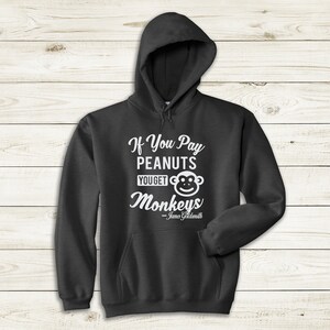 May include: A dark gray hooded sweatshirt with a white graphic print that reads "If You Pay Peanuts You Get Monkeys - James Goldsmith".