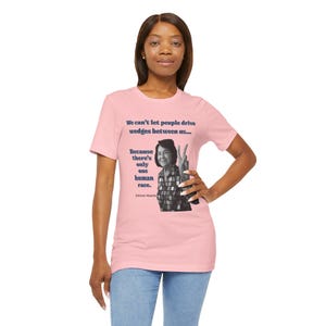 May include: Pink t-shirt with a quote by Dolores Huerta: "We can't let people drive wedges between us... Because there's only one human race."