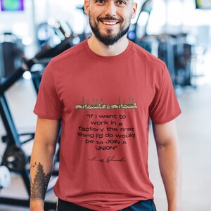Könnte beinhalten: Ein rotes T-Shirt mit einer schwarzen Grafik einer Fabriklandschaft und einem Zitat, das lautet: "Wenn ich in einer Fabrik arbeiten würde, wäre das erste, was ich tun würde, einem Gewerkschaftsverband beizutreten." Das Zitat wird "Frank "The Tank"  mit einer Unterschrift zugeschrieben.