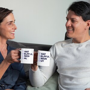 May include: Two people are smiling and holding white mugs with the words "That Helpful Union Gal" and "That Helpful Union Guy" printed on them.