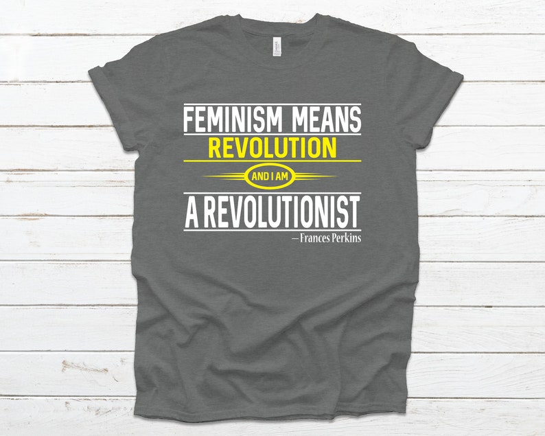 May include: A dark gray t-shirt with the text "Feminism means revolution and I am a revolutionist - Frances Perkins" in white and yellow lettering.