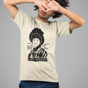 May include: Cream-colored t-shirt featuring a black and white portrait of Lucy Parsons, with text that reads "Never be deceived that the rich will permit you to vote away their wealth." The text "LUCY PARSONS" is below the portrait.