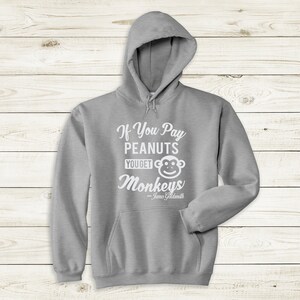 May include: Gray hooded sweatshirt with the text "If You Pay Peanuts You Get Monkeys" and a cartoon monkey face. The text "James Goldsmith" is below the monkey.