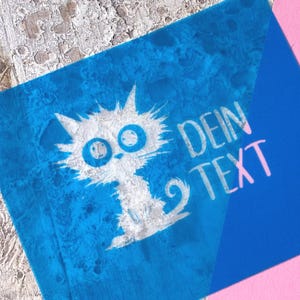 Könnte beinhalten: Ein blauer Quadrat mit einer weißen Katzenillustration und dem pinkfarbenen Text "DEIN TEXT". Die Katze hat große Augen und eine stachelige Kontur. Der Hintergrund hat einen strukturierten, aquarellartigen Effekt.